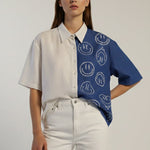 Woman wearing a white shirt with a blue patterned sleeve against a plain background