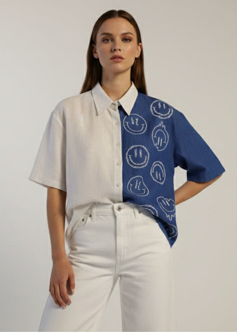Woman wearing a white shirt with a blue patterned sleeve against a plain background