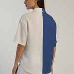 Woman wearing a white and blue color-blocked shirt on a plain background