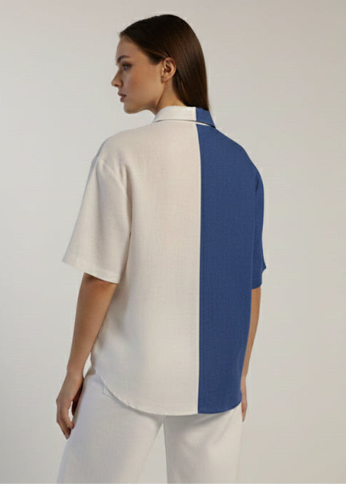 Woman wearing a white and blue color-blocked shirt on a plain background