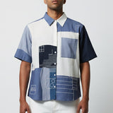 Man wearing a patterned shirt with geometric design on a plain background