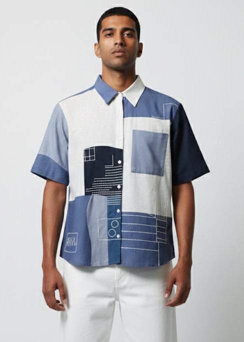 Man wearing a patterned shirt with geometric design on a plain background
