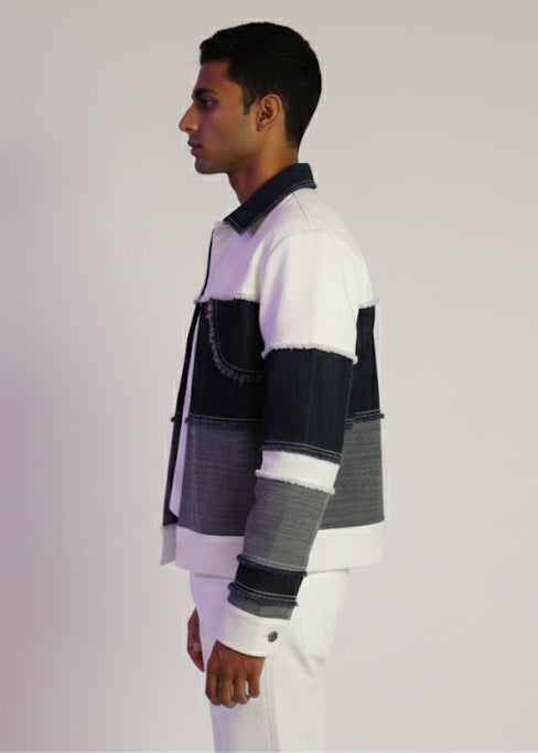 Man wearing a colorful striped sweater and white pants against a plain background