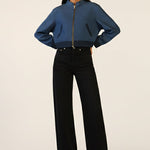 Person wearing a blue jacket and black pants on a white background