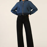 Person wearing a blue jacket and black pants on a white background
