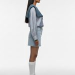 Person wearing a light blue outfit with white sneakers on a white background