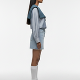 Person wearing a light blue outfit with white sneakers on a white background