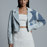 Woman wearing a stylish outfit with a textured jacket on a gray background