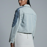 Woman wearing a light blue denim jacket and beige skirt on a gray background