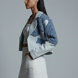 Woman wearing a blue jacket and white skirt on a gray background