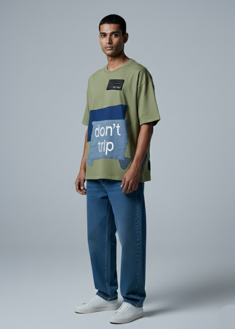 Man wearing a green t-shirt with a blue graphic and text, standing against a plain background