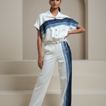 Woman wearing a white and blue striped outfit standing in a minimalistic setting.