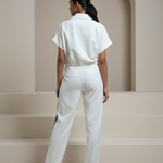 Person wearing a white outfit standing in a minimalistic setting with an archway.