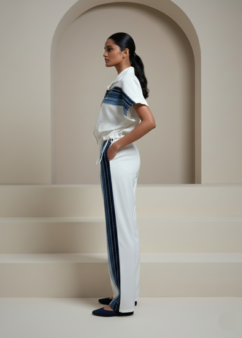 Woman wearing a white outfit with blue stripes in a minimalistic setting