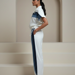 Woman wearing a white outfit with blue stripes in a minimalistic setting