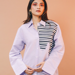 Woman wearing a light purple shirt with a striped pattern on a beige background