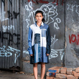Person wearing a blue and white outfit standing in front of a graffiti-covered wall.